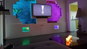 Un salon moderne avec un téléviseur à écran plat fixé au mur, le tout agrémenté de motifs géométriques lumineux.