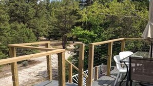 A wooden deck with a table and chairs, surrounded by a railing and trees. - Lake house 30 minutes from North Conway, NH! (Brownfield)