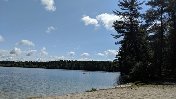 A sandy beach with a calm lake, surrounded by dense trees and a clear sky. - Lake house 30 minutes from North Conway, NH! (Brownfield)
