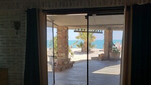 Una habitación con puerta corrediza de vidrio que da a un patio con vista a la playa y el océano.