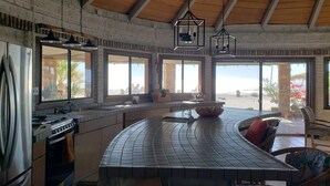 Una cocina con una isla curva, ventanas amplias y vista a la playa.