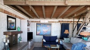 Una sala de estar acogedora con chimenea, televisor, un cuadro grande y una escalera.