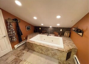 Un bagno con una vasca da bagno ampia, una doccia e un lavabo con specchio.