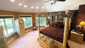 Ein Schlafzimmer mit einem Himmelbett, einem Deckenventilator und großen Fenstern.
