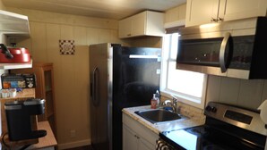 A compact kitchen with a refrigerator, microwave, stove, and sink. - Cozy casita: Bastrop state park view (Bastrop)