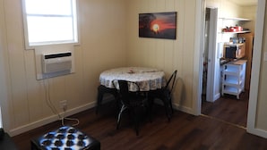 A dining area with a table and chairs, a painting on the wall, and a kitchen in the adjacent room. - Cozy casita: Bastrop state park view (Bastrop)