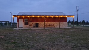 A small building with a porch, a door, and a bench. - Lovely one room barndominium - The Bastrop Barndo  (Bastrop)