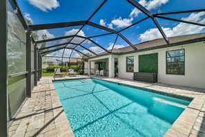 A swimming pool with a glass ceiling, surrounded by a patio area with seating and a view of the sky. - Cape Coral Oasis Centrally Located on Fresh Water Canal (Cape Coral)