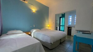 Une chambre d’hôtel avec deux lits, une petite table, un bureau et une salle de bain visible à travers une porte ouverte.