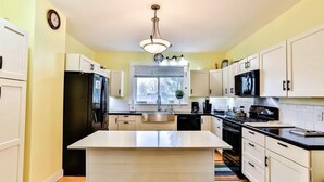 A modern kitchen with white cabinetry, a central island, a built-in oven, and a microwave. - Stately home by Spirit Lake in Menahga (Menahga)