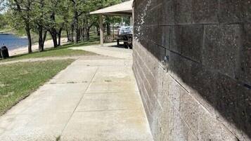 A concrete pathway leading to a covered area with a stone wall on one side.