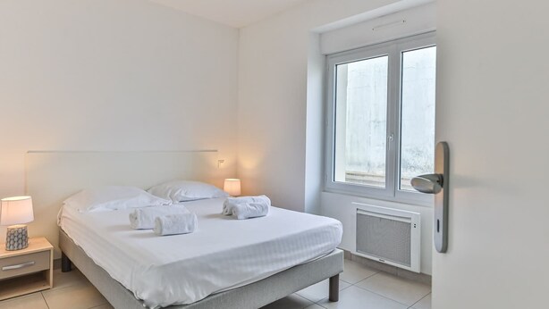 Une chambre d’hôtel moderne équipée d’un lit, de lampes de chevet, d’une fenêtre et d’un radiateur.