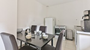 Une cuisine compacte comprenant une table à manger, des chaises, un réfrigérateur, un four et une machine à café.