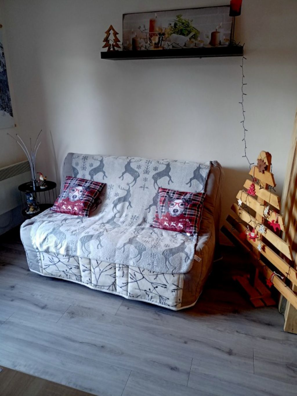 A cozy living room with a sofa, a small table with a decorative item, and a wall-mounted shelf with a painting.