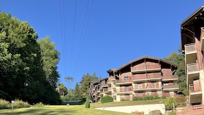 A hotel with multiple balconies, a grassy lawn, and a clear blue sky.