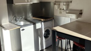 A compact kitchen with a washing machine, a sink, and a countertop.