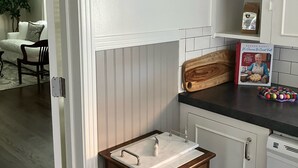 Una cucina con un armadietto bianco, un piccolo tavolo di legno e un cartello appeso al muro con la scritta 'keep life simple'.