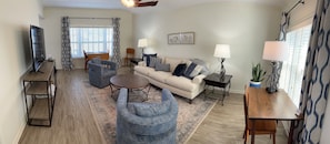 A living room with a sofa, two armchairs, a coffee table, a TV, and a dining table.