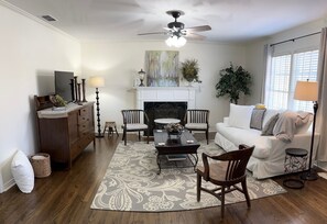 A living room with a fireplace, a ceiling fan, a sofa, a coffee table, and a TV.