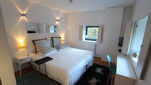 Une chambre à coucher comprenant un lit, des tables de chevet, un bureau, une chaise, une fenêtre et un miroir.