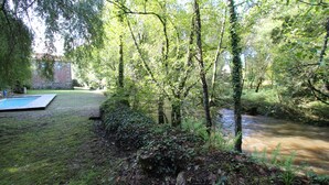 Un espace extérieur aménagé, avec une piscine, un petit bâtiment et un ruisseau.