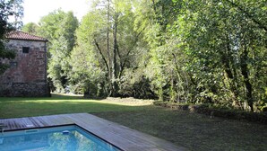 Une piscine dotée d’une terrasse en bois, entourée d’une pelouse et d’arbres.