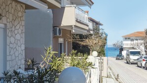 Una hilera de edificios modernos con balcones que dan a una calle pavimentada y una masa de agua.