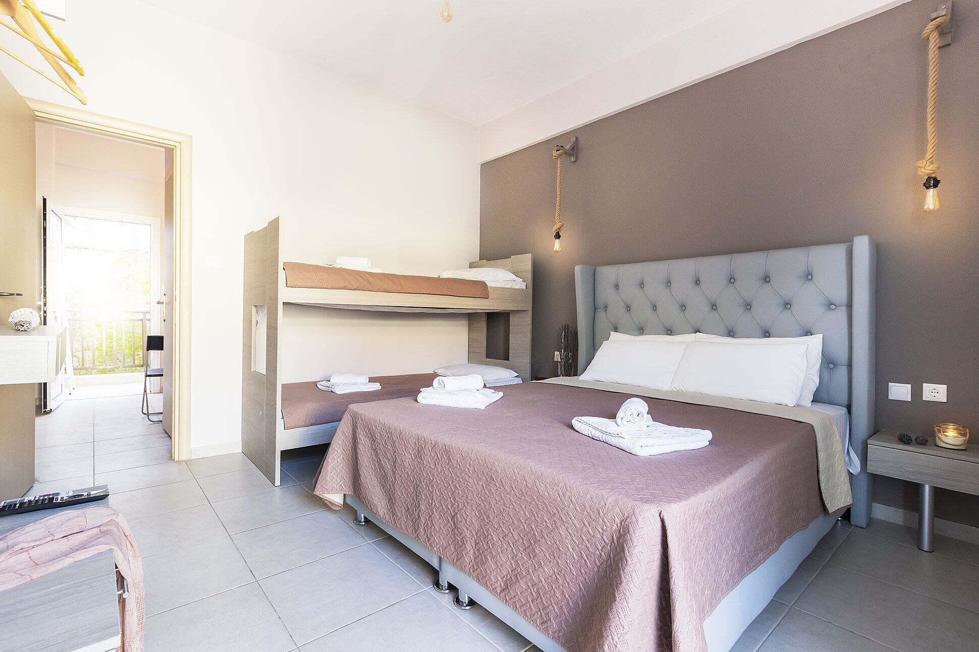 Een hotelkamer met een stapelbed, een enkel bed en een bureau met stoel.