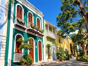 A row of colorful buildings with balconies and potted plants.