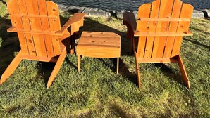 A covered outdoor seating area with Adirondack chairs and a small table, overlooking a pond with a water feature and a rainbow. - Willow Springs Resort (Bridgeport)