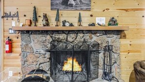 A stone fireplace with a fire, surrounded by wooden walls and a bear-themed decor.