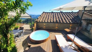 A wooden deck with a hot tub, lounge chairs, and a view of a mountain range. - Casa Melograno.  3 bedrooms, 2 bathrooms, Spa-pool, patio, sea &  valley views (Gombitelli)