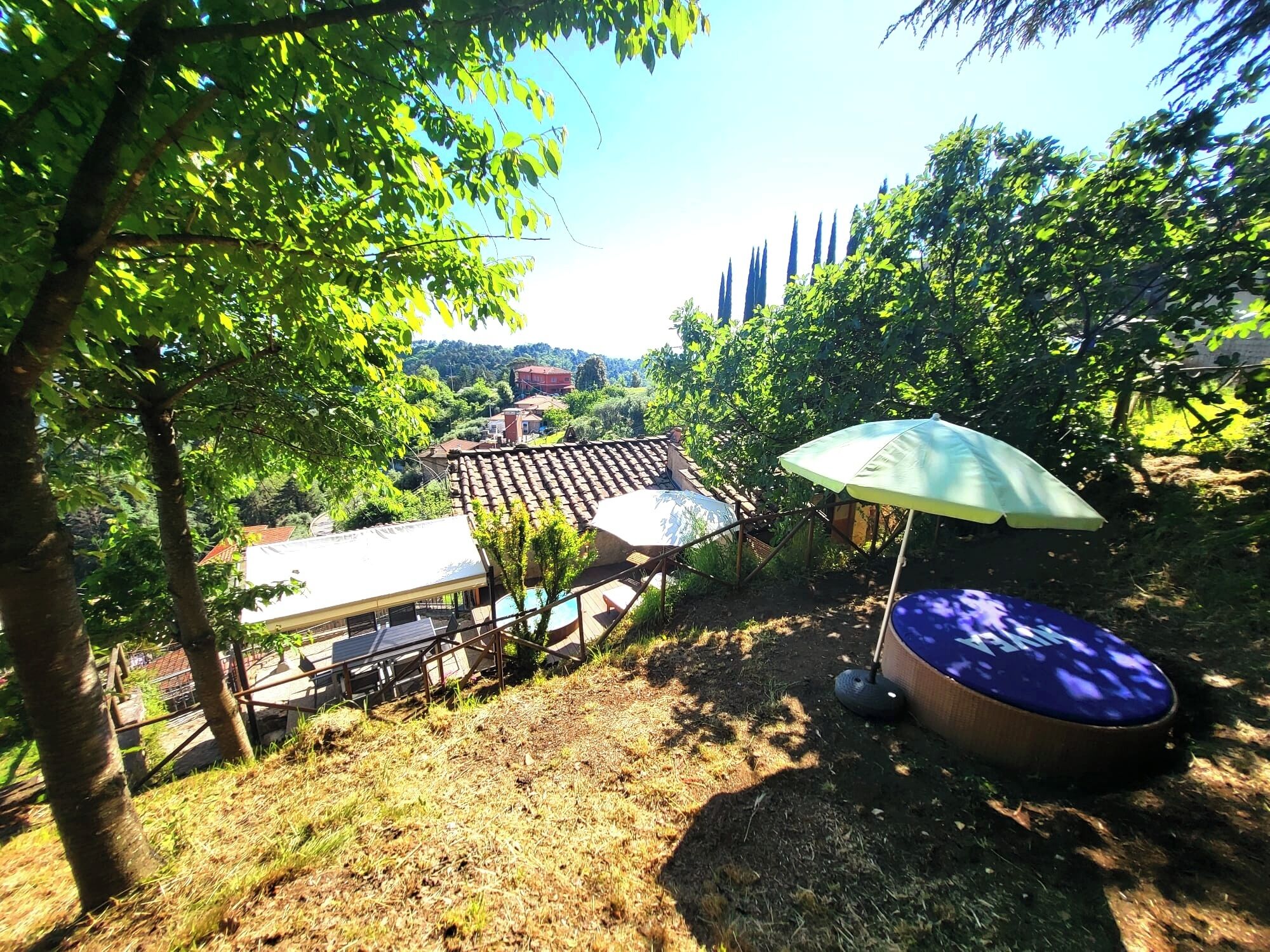 Un espace patio avec une table et des chaises, une piscine et une pergola dotée d’un parasol.