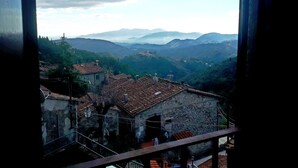 A view from a window overlooking a mountainous landscape with traditional stone buildings and terracotta roofs. - Casa Melograno.  3 bedrooms, 2 bathrooms, Spa-pool, patio, sea &  valley views (Gombitelli)