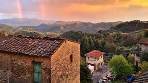 A rustic building with a tiled roof, surrounded by lush greenery and mountains in the background. - Casa Melograno.  3 bedrooms, 2 bathrooms, Spa-pool, patio, sea &  valley views (Gombitelli)
