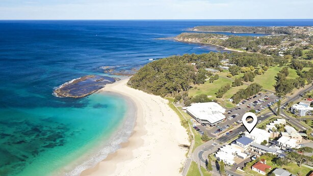An aerial view of a coastal area with a beach, clear waters, and a residential area with houses and roads. - Beachfront 2 - Steps away from the prestine waters of Mollymook Beach (Mollymook)