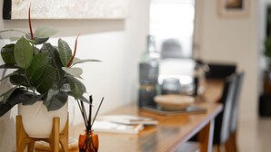 A dining area with a wooden table, a potted plant, and a vase with reed sticks. - Beachfront 2 - Steps away from the prestine waters of Mollymook Beach (Mollymook)