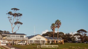 A building labeled 'MOLLYMOOK SURF CLUB' with a balcony, a wind turbine, and surrounding trees.