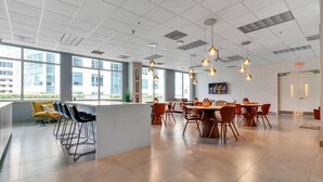A modern dining area with a high ceiling, large windows, and a mix of bar and dining tables. - Fabulous Two Bedrooms Brickell+ Free Parking (Miami)