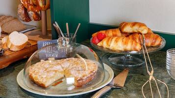 Un bufé con diversas opciones de panadería, incluyendo pan, pasteles y un postre cubierto.