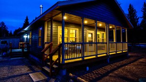 A wooden cabin with a porch, a chimney, and a small deck area.