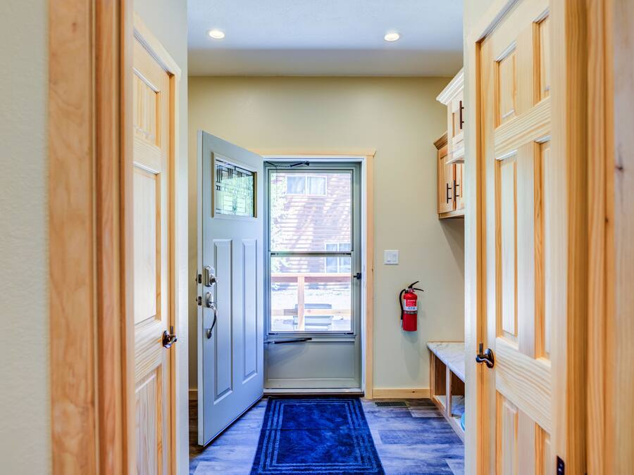 Un couloir avec des portes en bois, un tapis bleu et un extincteur accroché au mur.