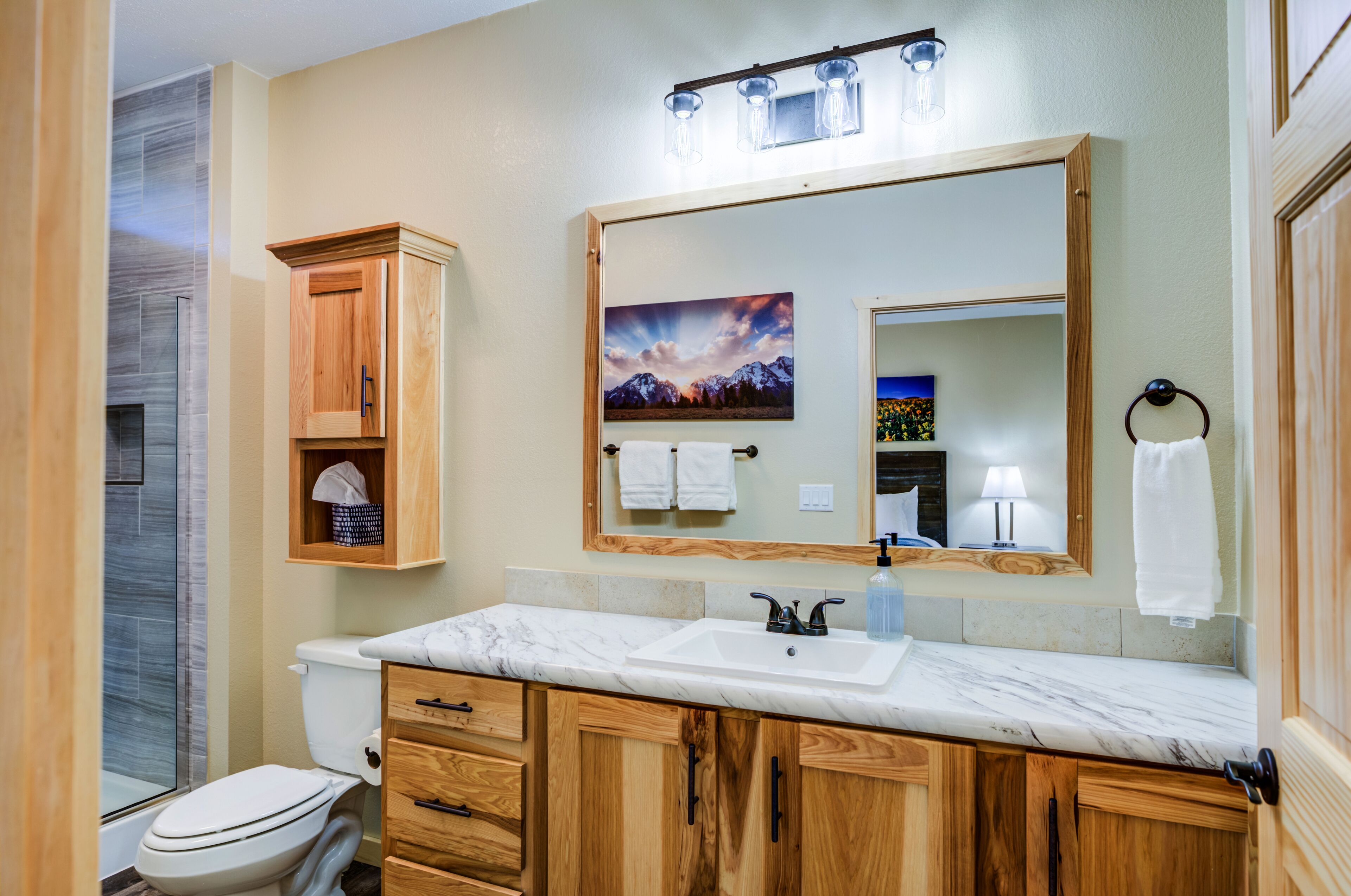 A bathroom with a marble sink, wooden cabinets, a large mirror, and a shower enclosure.