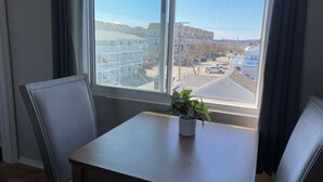 A room with a large window, a small table with a potted plant, and two chairs. - Ways Motel (Hampton)
