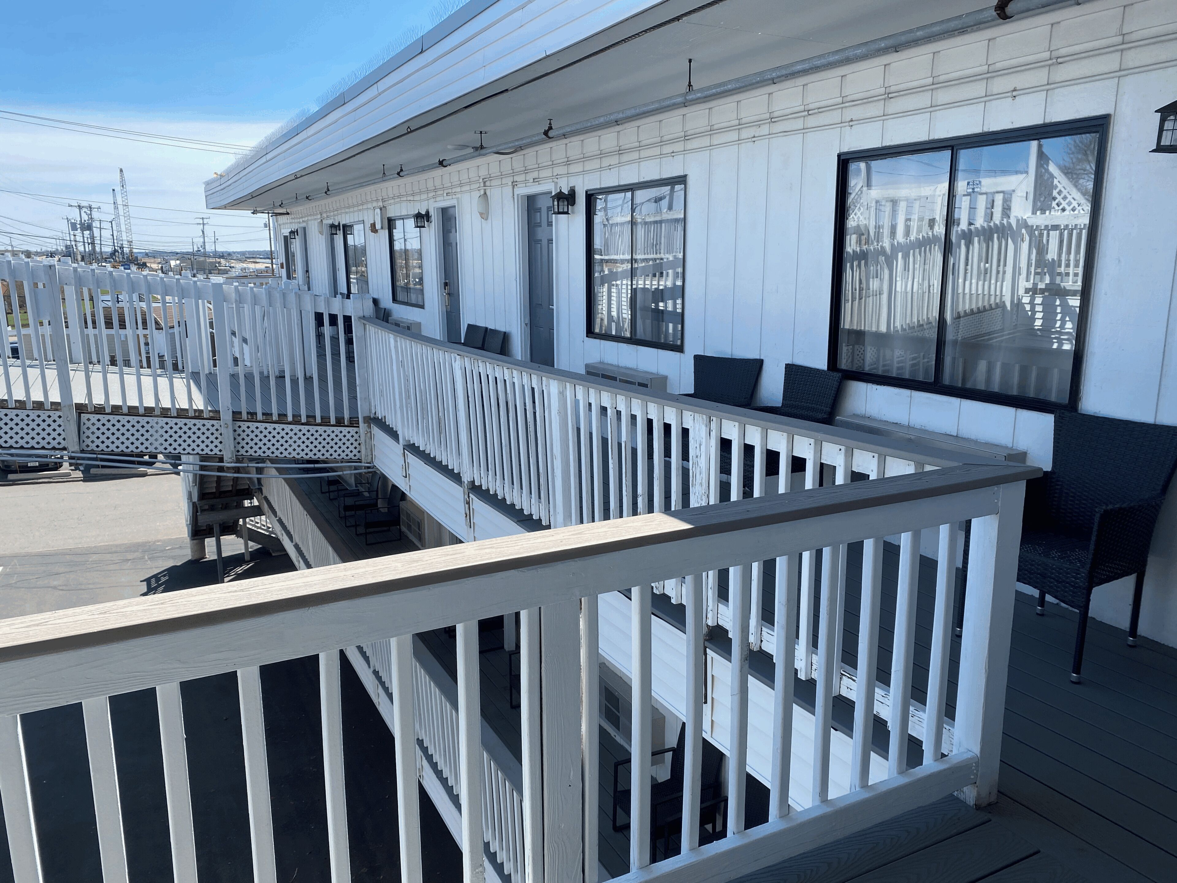 A deck with white railings, black chairs, and a view of the city skyline.