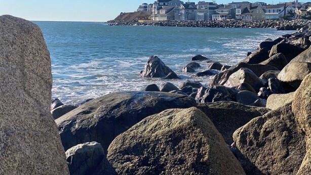 A coastal area with large rocks in the foreground and houses in the background. - Ways Motel (Hampton)