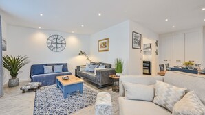 A modern living room with two sofas, a coffee table, and a dining area with chairs and a table.