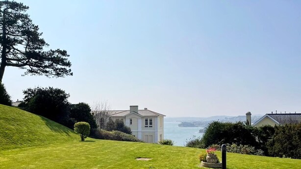 A house with a lawn and a view of the sea.