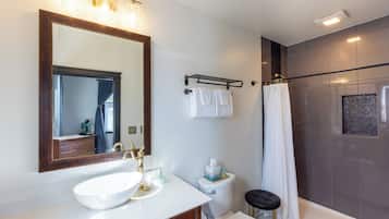 Ein Badezimmer mit großem Spiegel, Waschbecken, Toilette und Duschbereich.