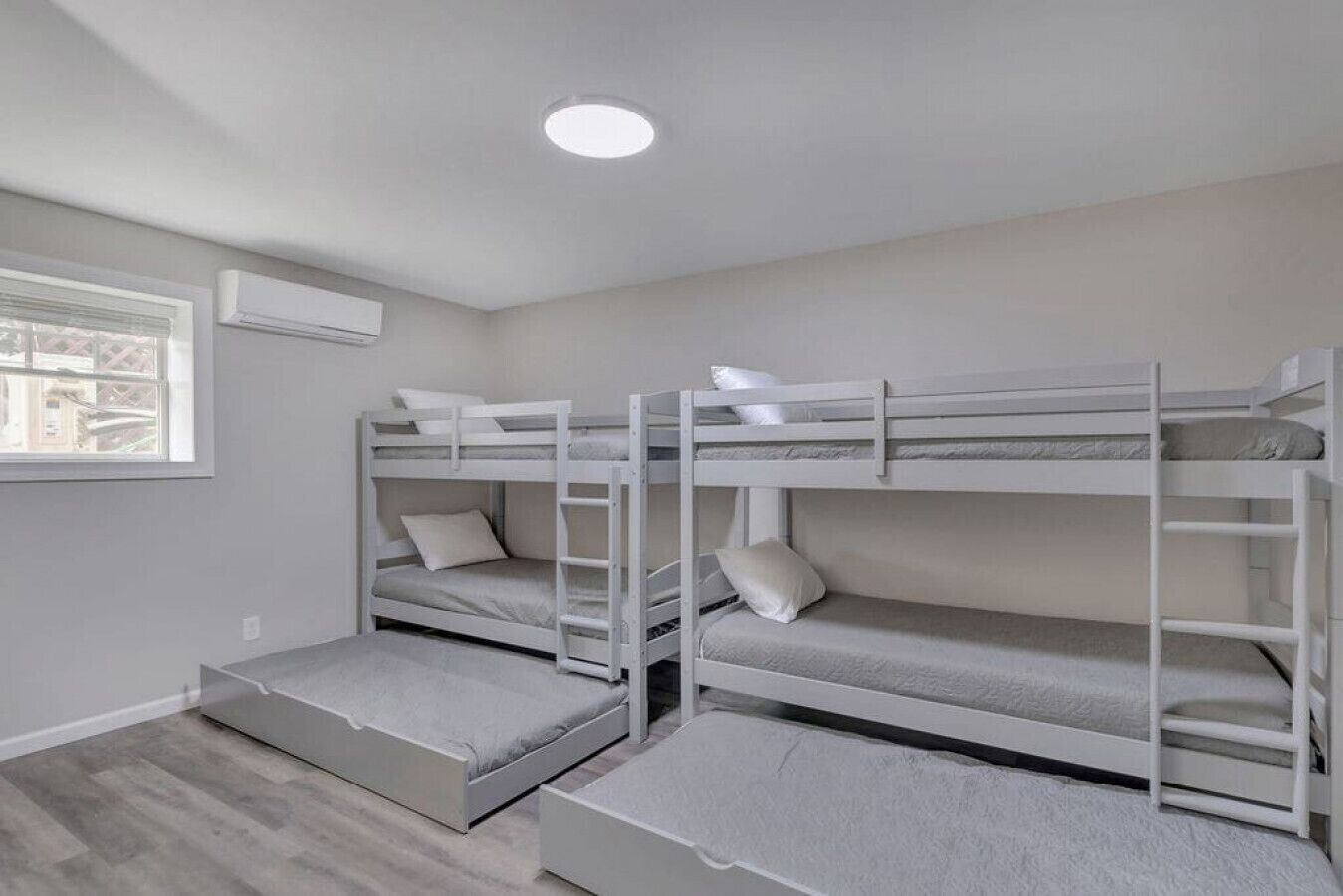 A room with bunk beds, a window, and a ceiling light.